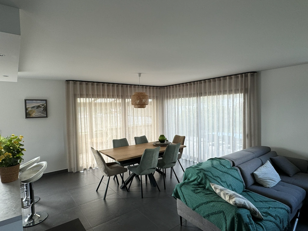 Voilages ondulés sur mesure dans une salle à manger avec baie d'angle panoramique